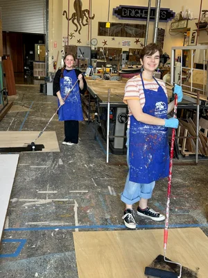 Two people backstage working on sets